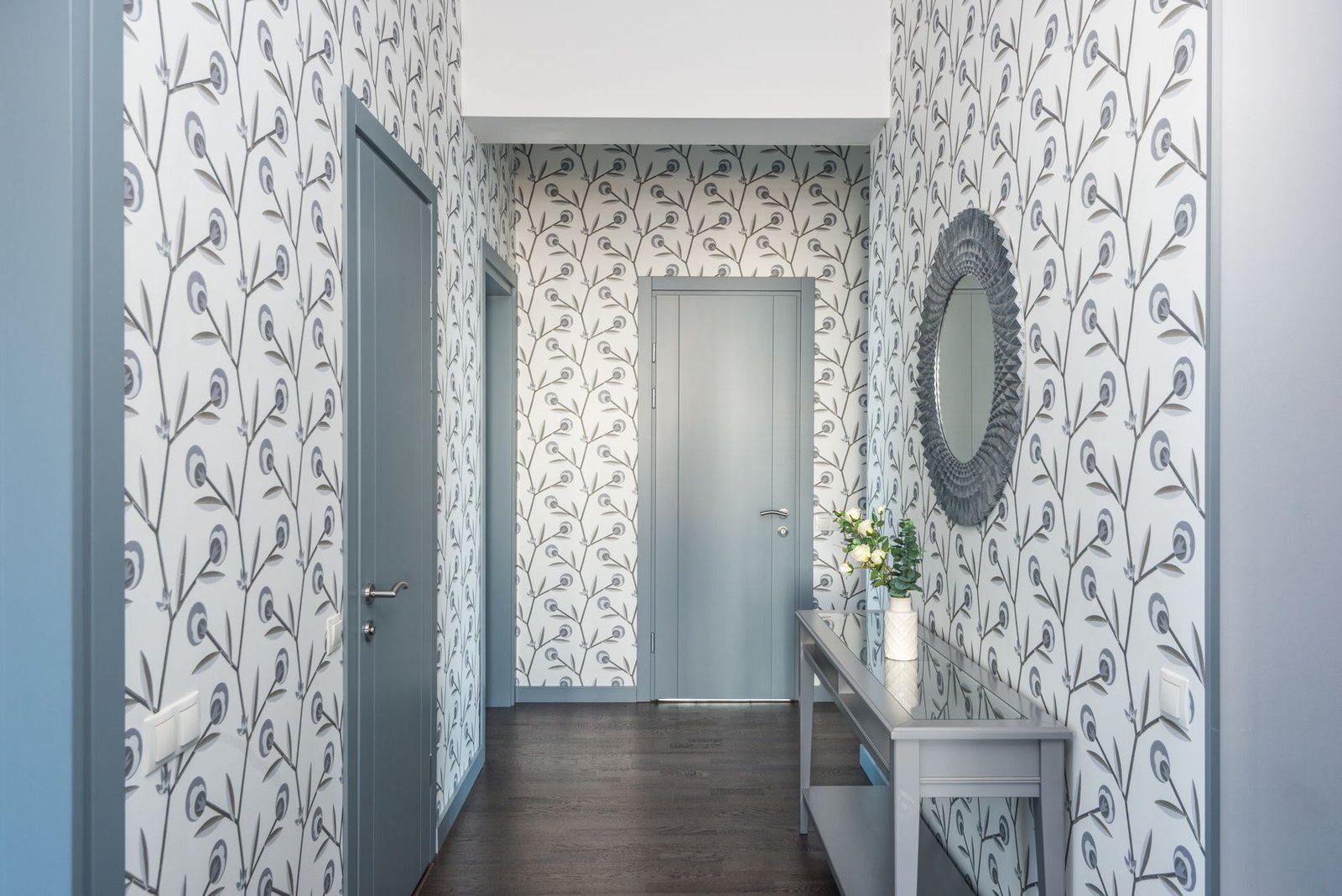 entryway organization — A stylish hallway featuring floral wallpaper, a console table, and a decorative mirror.