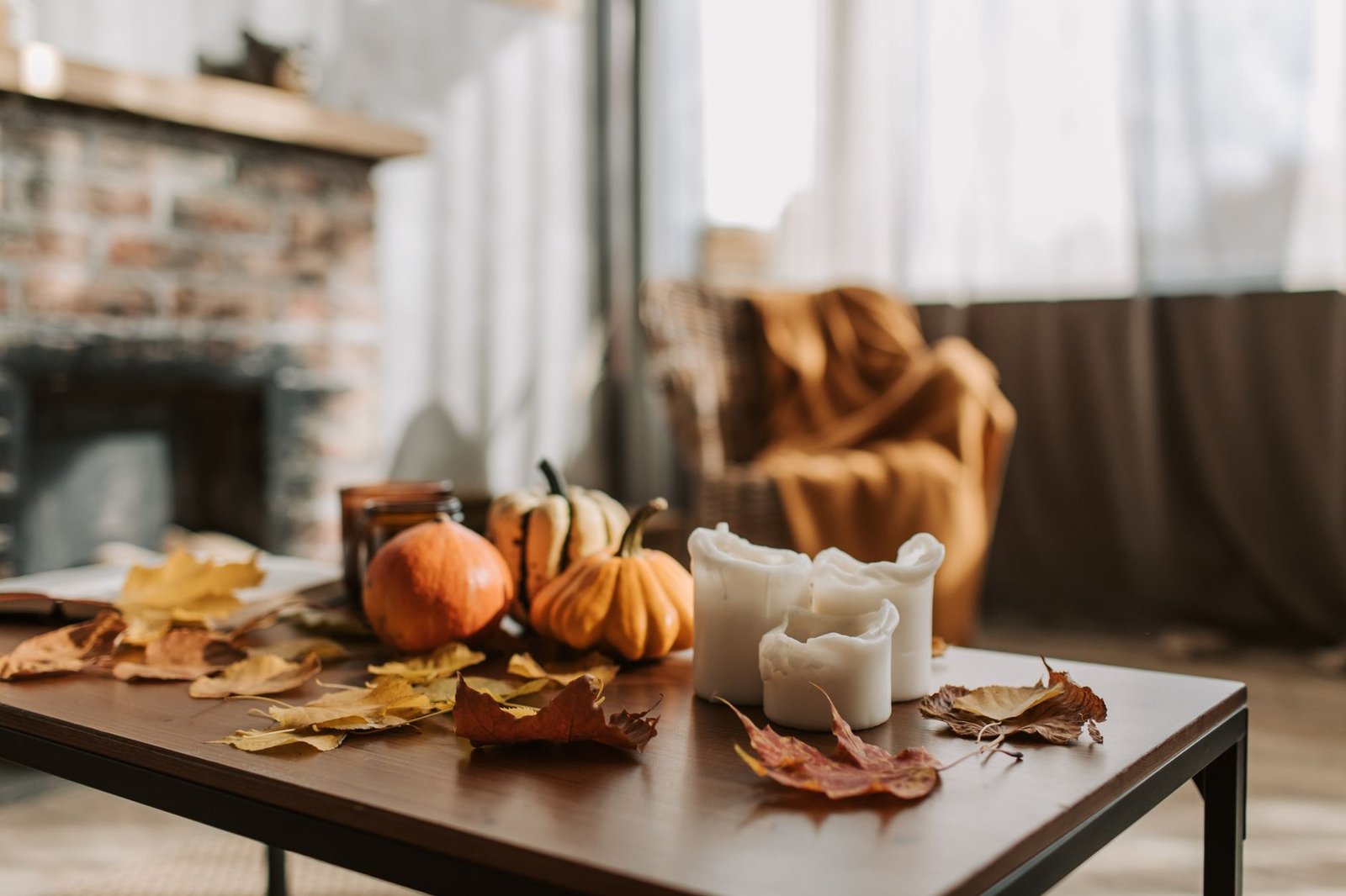 fall reset checklist — Warm indoor autumn setting with candles, pumpkins, and dried leaves on a wooden table, creating a cozy atmosphere.