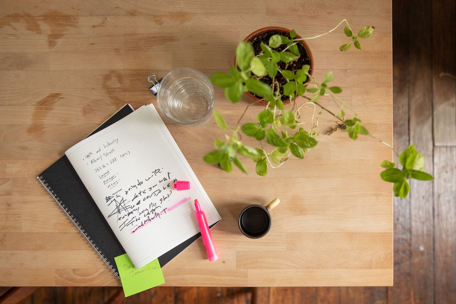 Overhead view of a workspace with notebooks, plant, and highlighter.