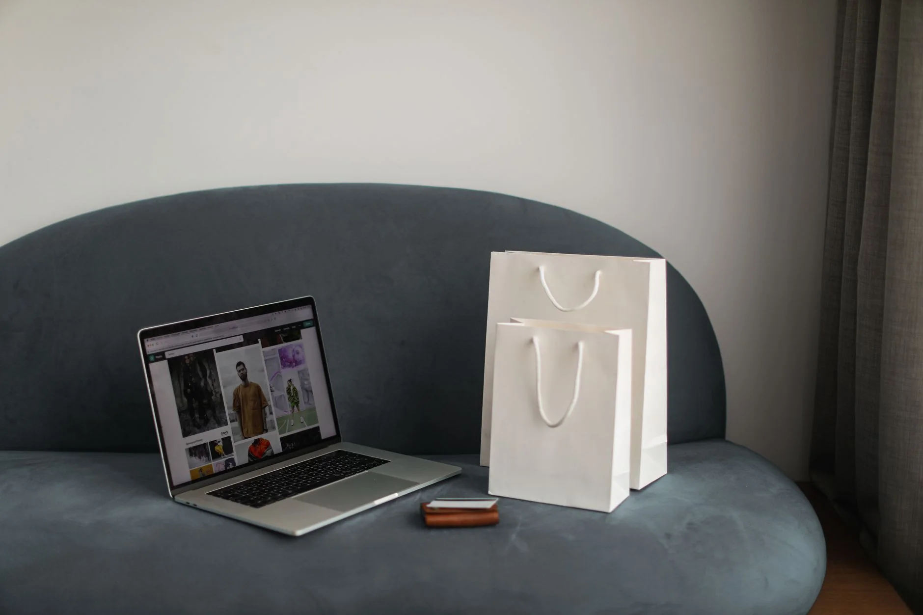 black friday shopping plan — Online shopping setup with a laptop and shopping bags on a stylish couch.
