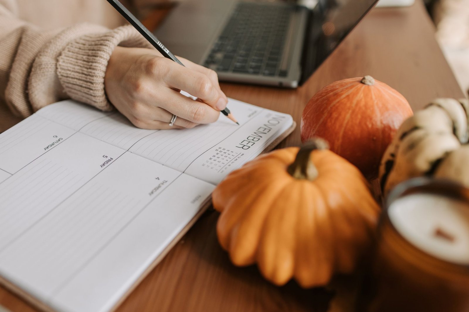 christmas planning timeline — A cozy workspace with a planner, pumpkins, and a laptop, capturing the essence of autumn planning.