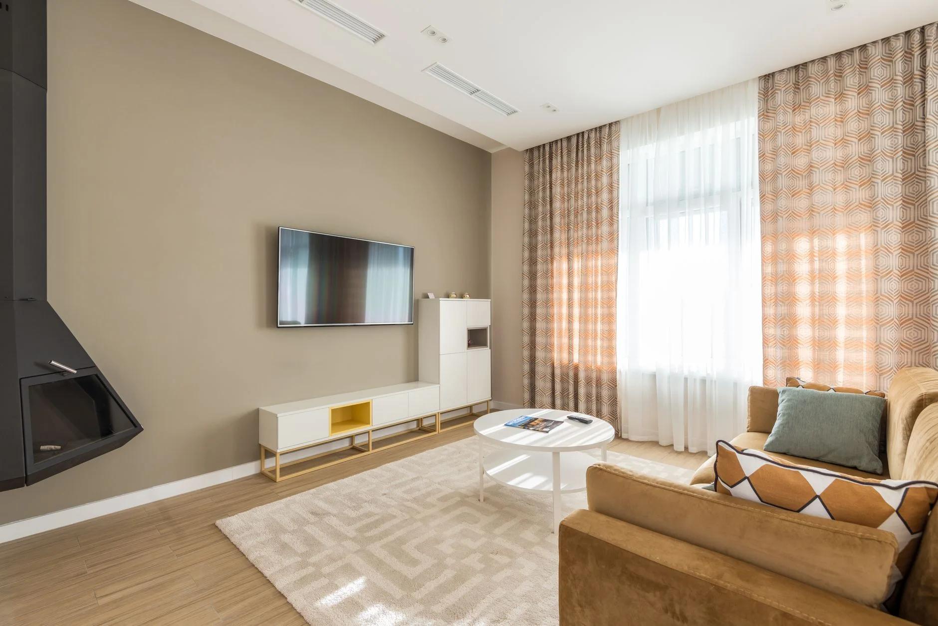 Bright modern living room with a sofa, coffee table, and large window curtains.