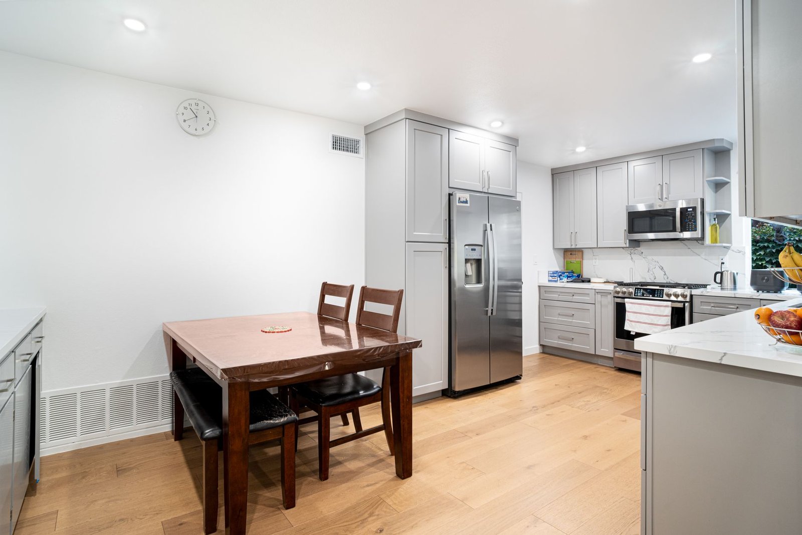 family command center — Spacious minimalist kitchen featuring sleek cabinetry, stainless steel appliances, and a wooden dining table.