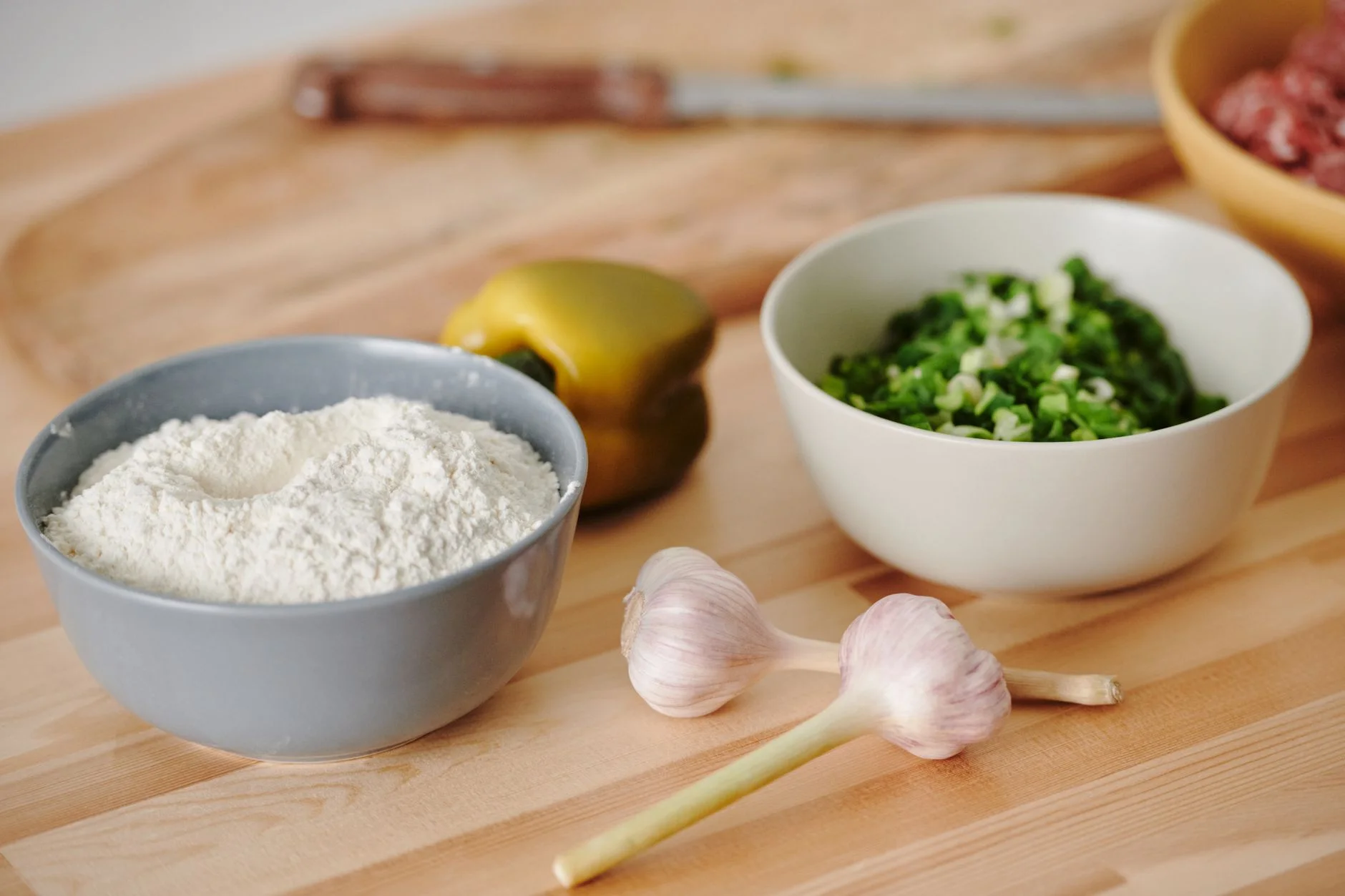 Fresh ingredients including flour, garlic, and scallions for cooking preparation.