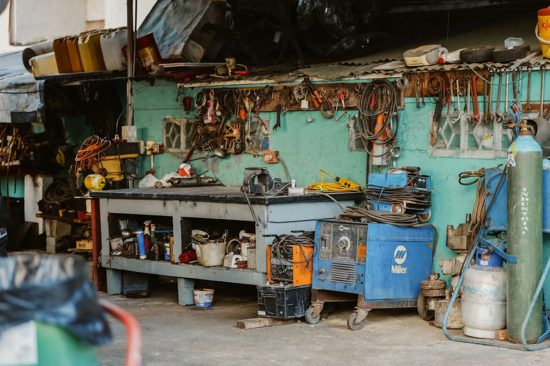 garage organization — A cluttered workshop with tools, welding equipment, and storage solutions.
