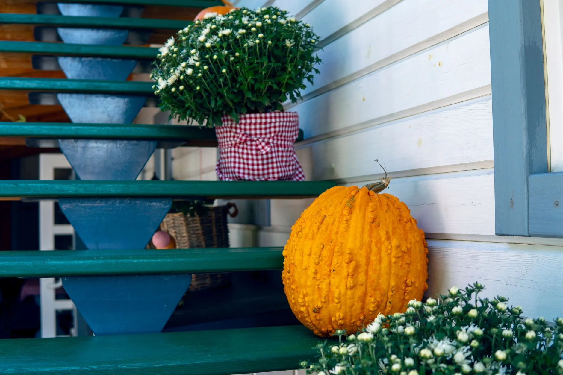 halloween on a budget — Charming autumn decor with pumpkin and flowers on wooden outdoor stairs, perfect for fall ambiance.