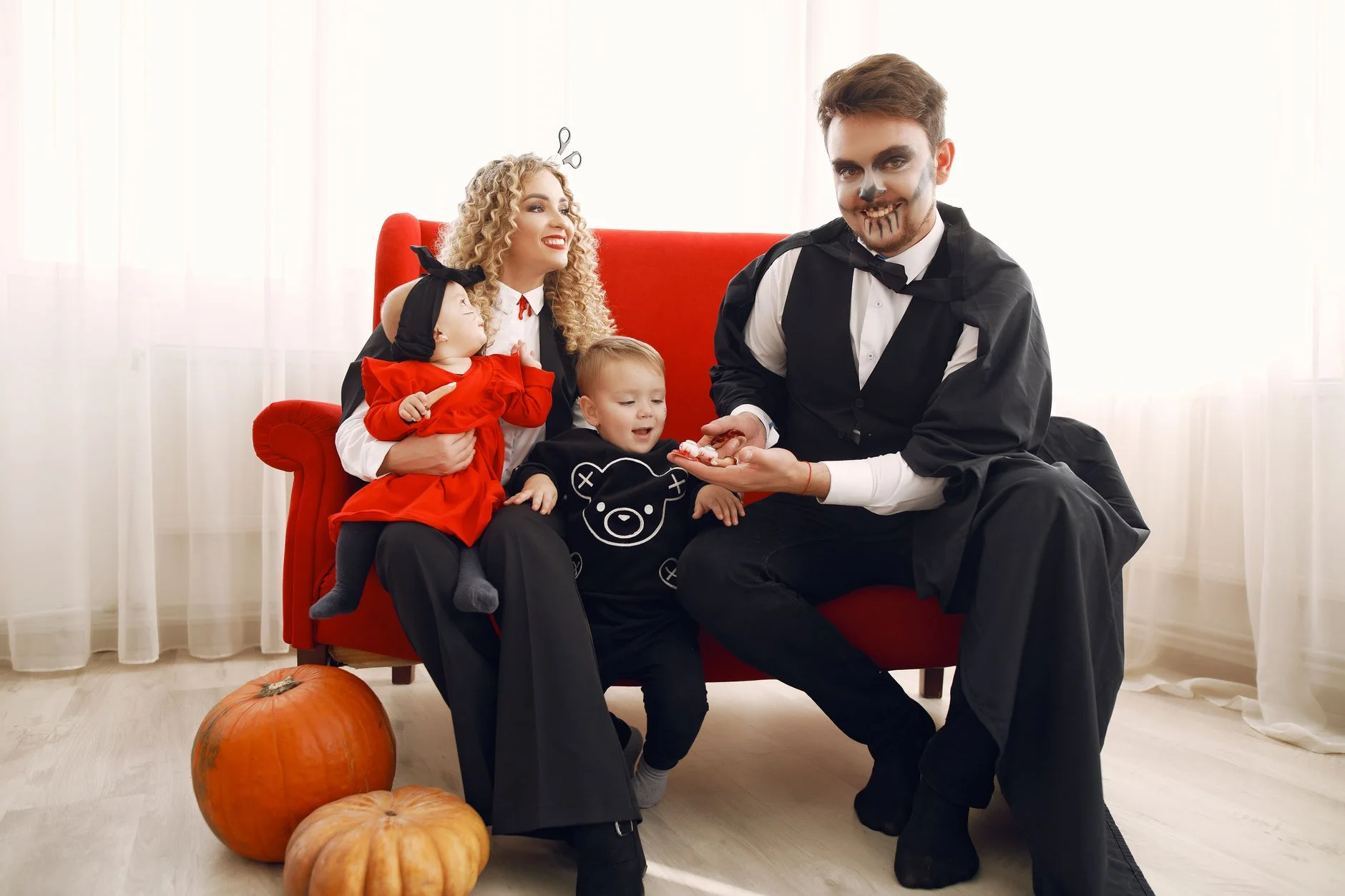 A family enjoying Halloween in costumes with pumpkins indoors.
