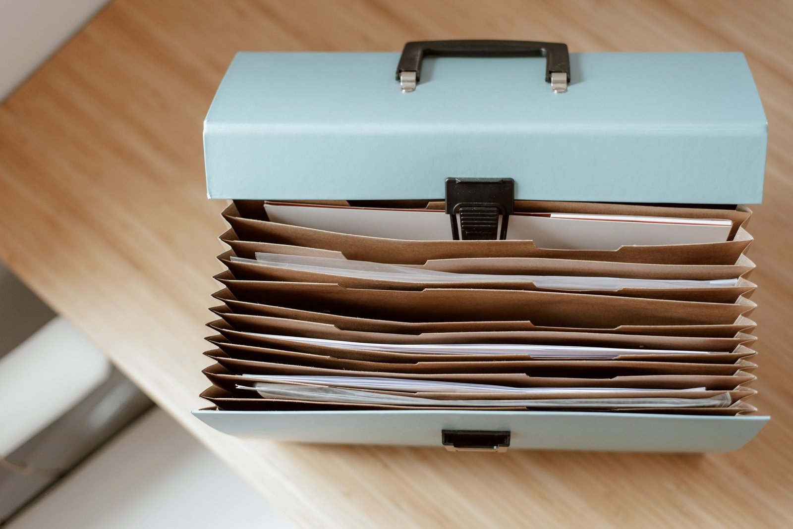 how to organize paperwork at home — From above of briefcase for documents with papers placed on wooden table in daytime
