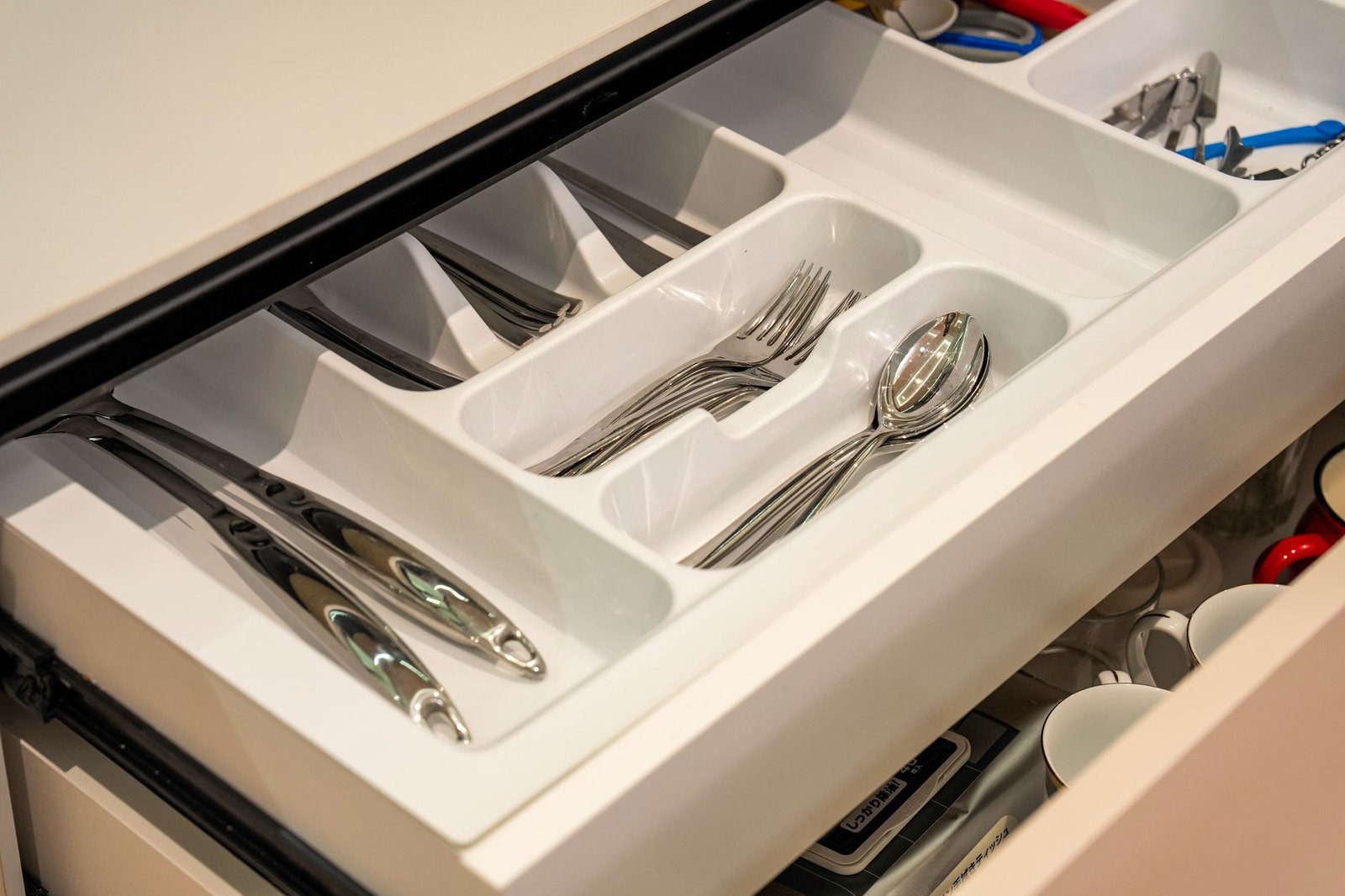 Neatly arranged silverware in a kitchen drawer with plastic organizer for efficient storage.