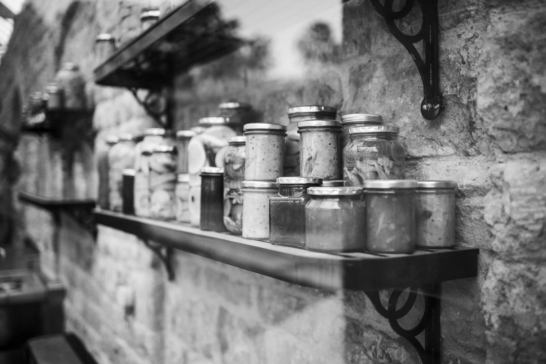 pantry organization — Black and white image of glass jars on rustic shelves indoors.