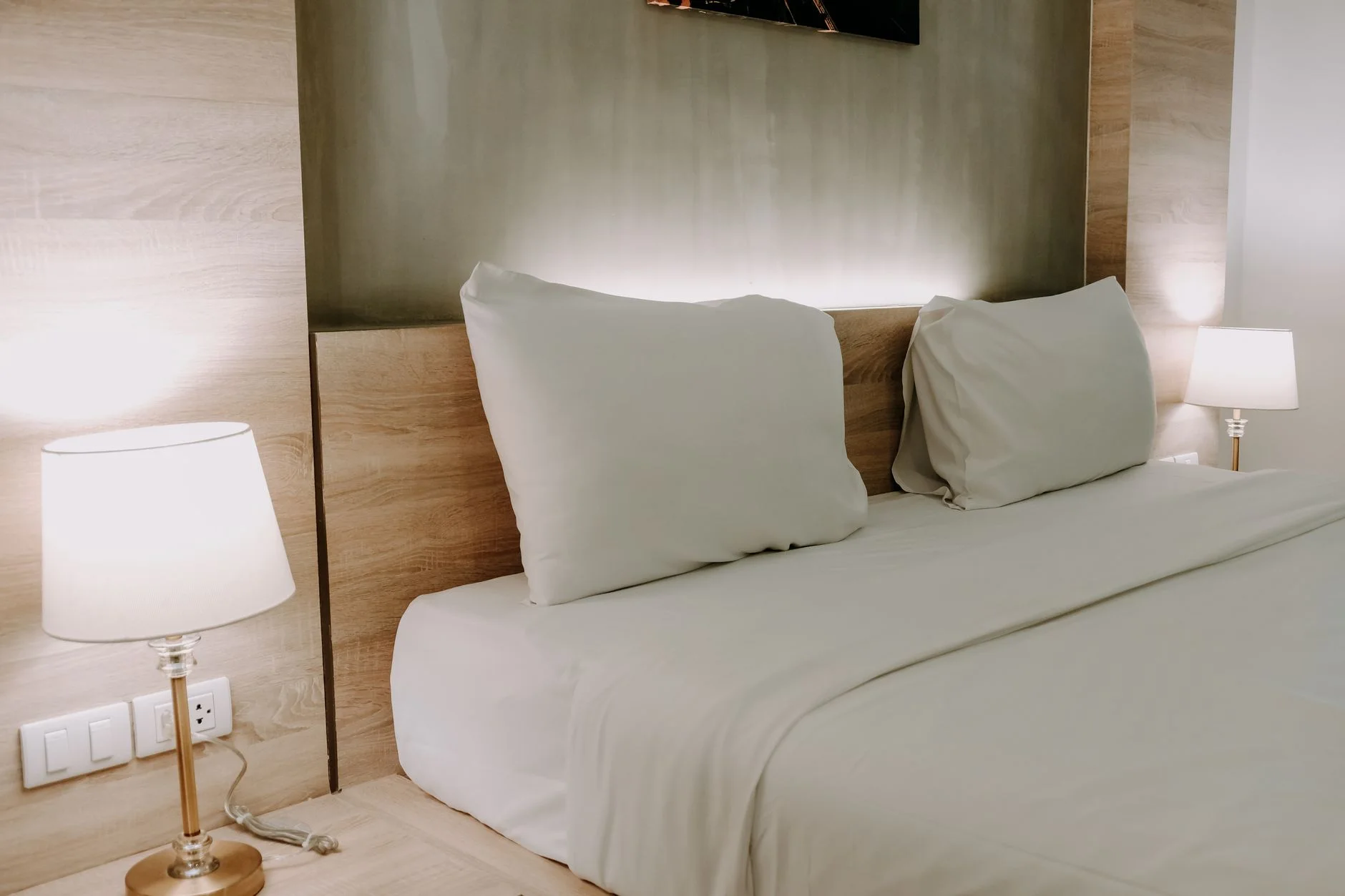 preparing for house guests — A modern bedroom with a minimalist design featuring a cozy bed with neutral bedding and warm ambient lighting.