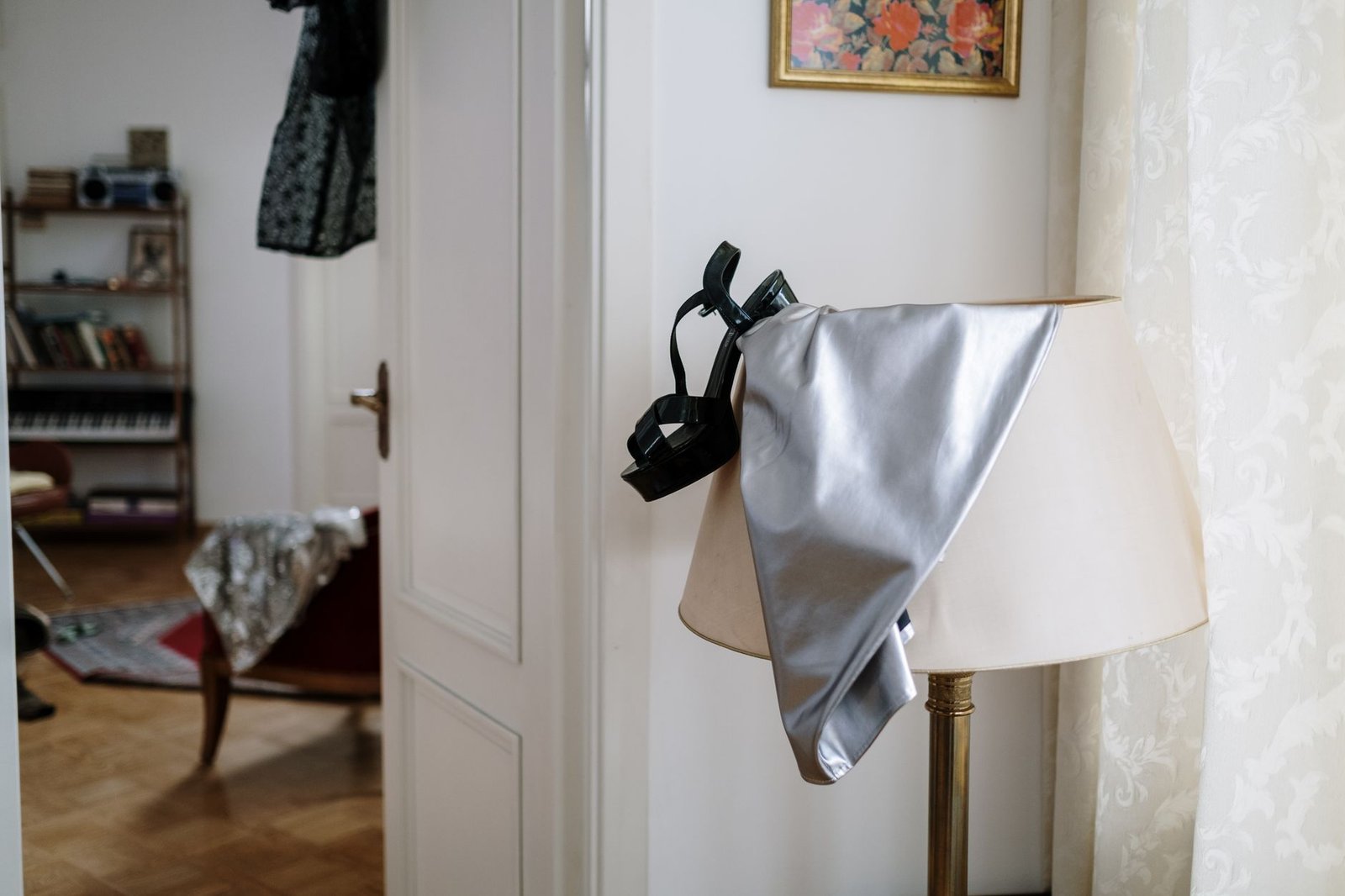 Elegant indoor scene with a lamp draped in a silver fabric and black heels, creating a sophisticated atmosphere.