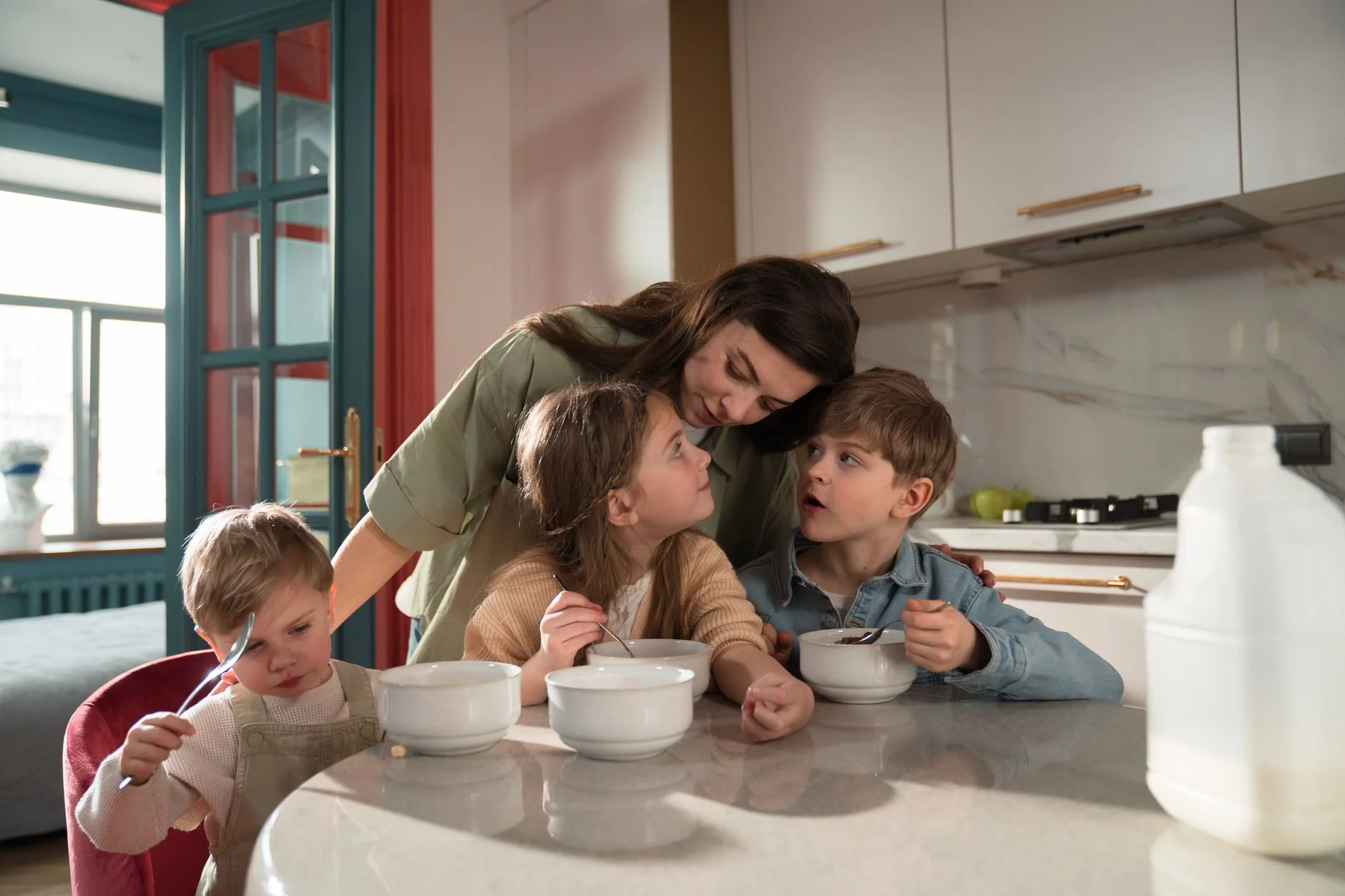 A mother and her children enjoy breakfast together in a cozy kitchen setting.