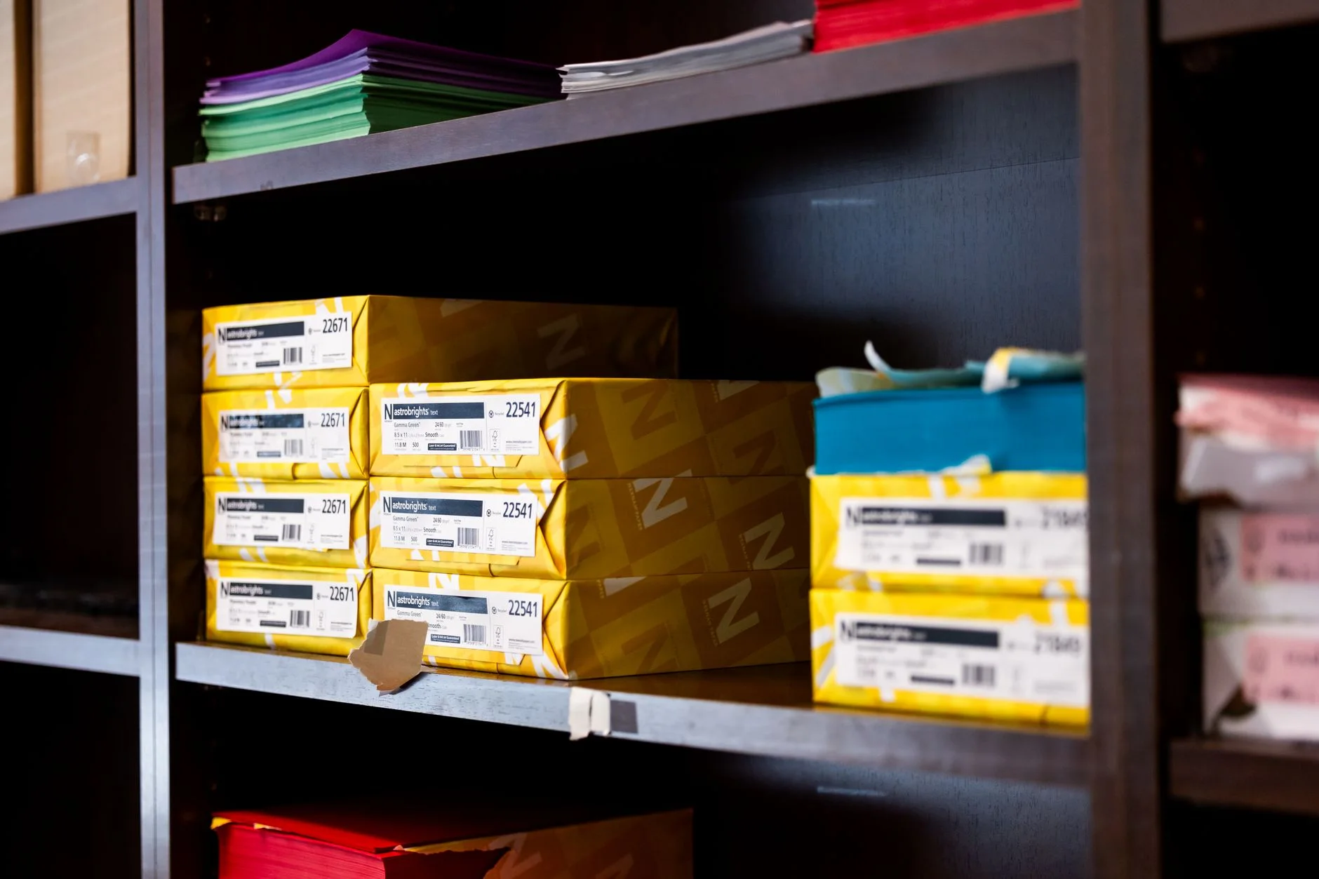 Stock photo of a shelf with colorful paper boxes for office supplies.