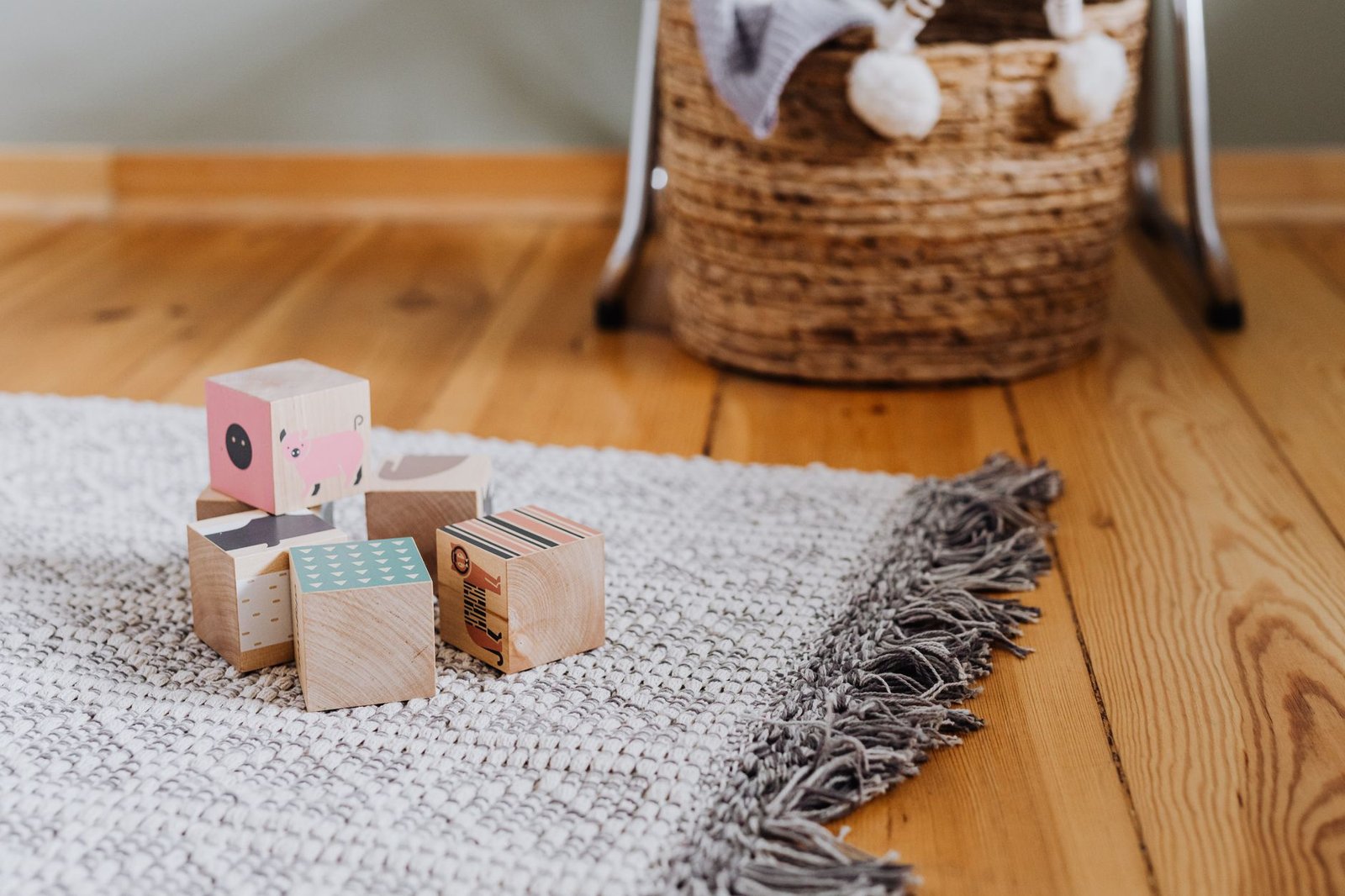 toy rotation — Colorful wooden blocks on woven rug in a cozy indoor playroom setting.