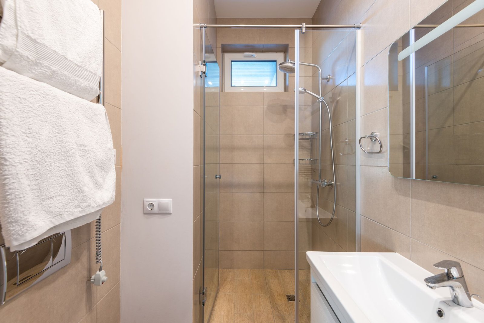 weekly cleaning schedule — Contemporary bathroom featuring a glass shower, beige tiles, and a sleek sink area.
